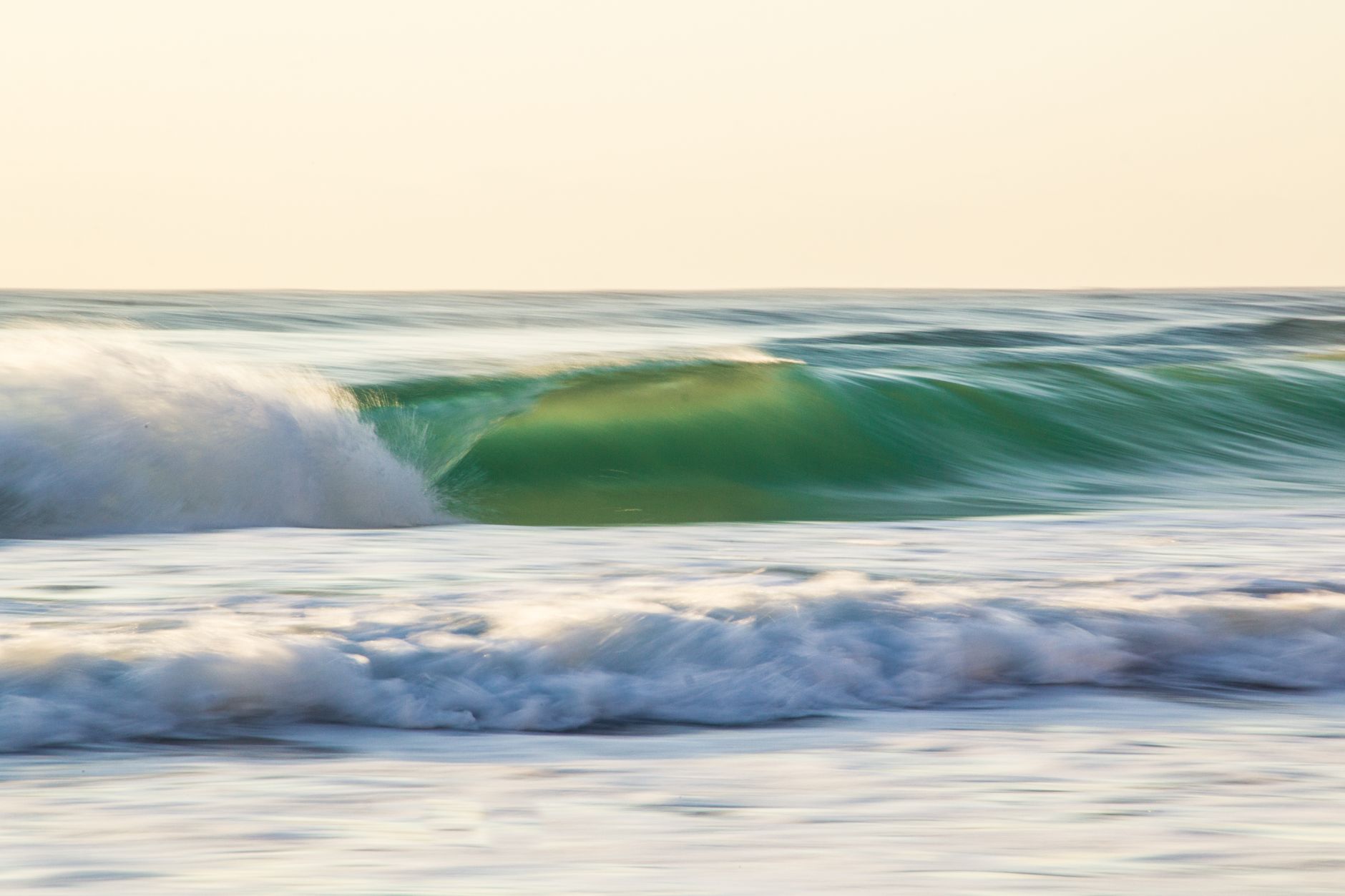 Beautiful ocean waves captured with motion blur, creating a serene seascape during sunset.