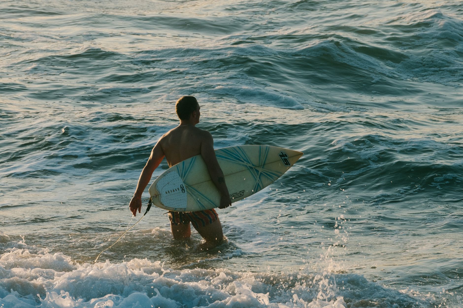 A surfer enters the ocean at Ballito Beach, KwaZulu-Natal, South Africa during the day.