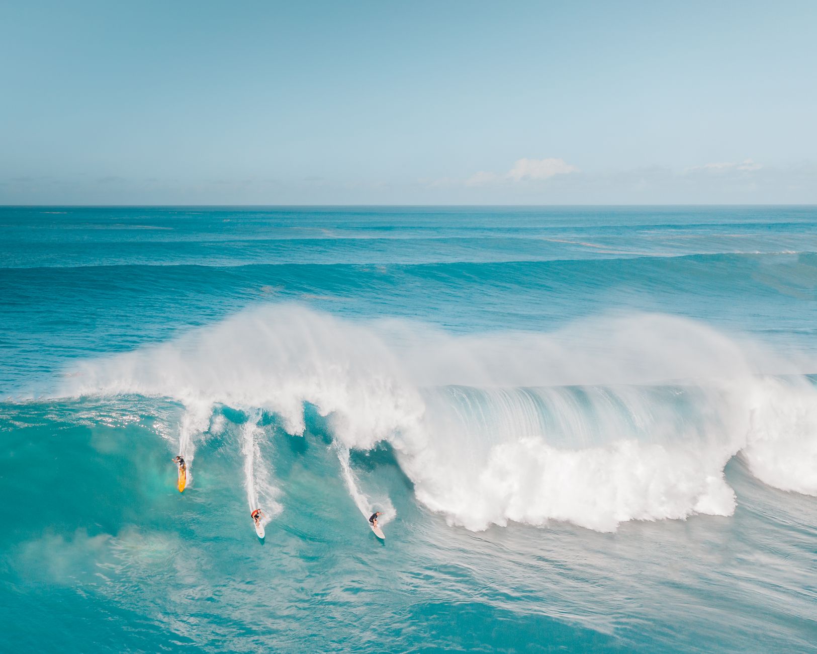 Surfers riding massive waves at Waimea Bay, capturing the thrill of Hawaiian surfing adventure.