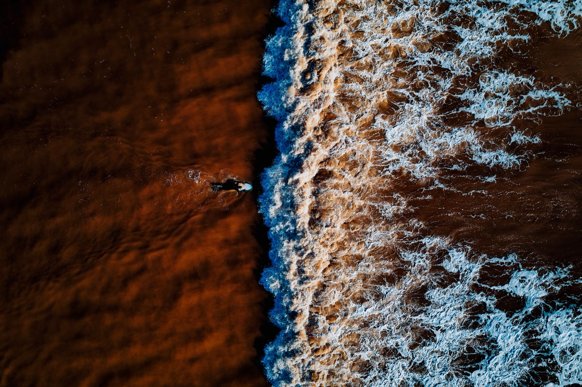Aerial view of a surfer navigating the waves in Sidmouth, England. Exciting water sport scene.