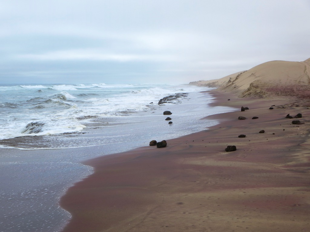 Atlantic waves crash into sandy Namib Desert shores south of Walvis Bay, Namibia.
